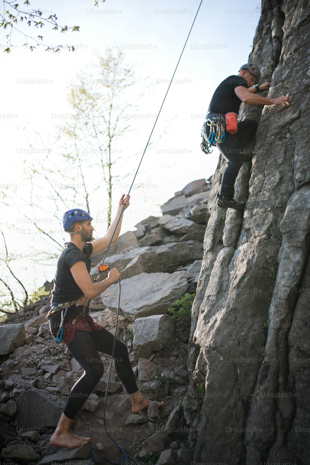 Retrato de un hombre mayor con instructor que escala rocas al aire libre en la naturaleza, estilo de vida activo.
