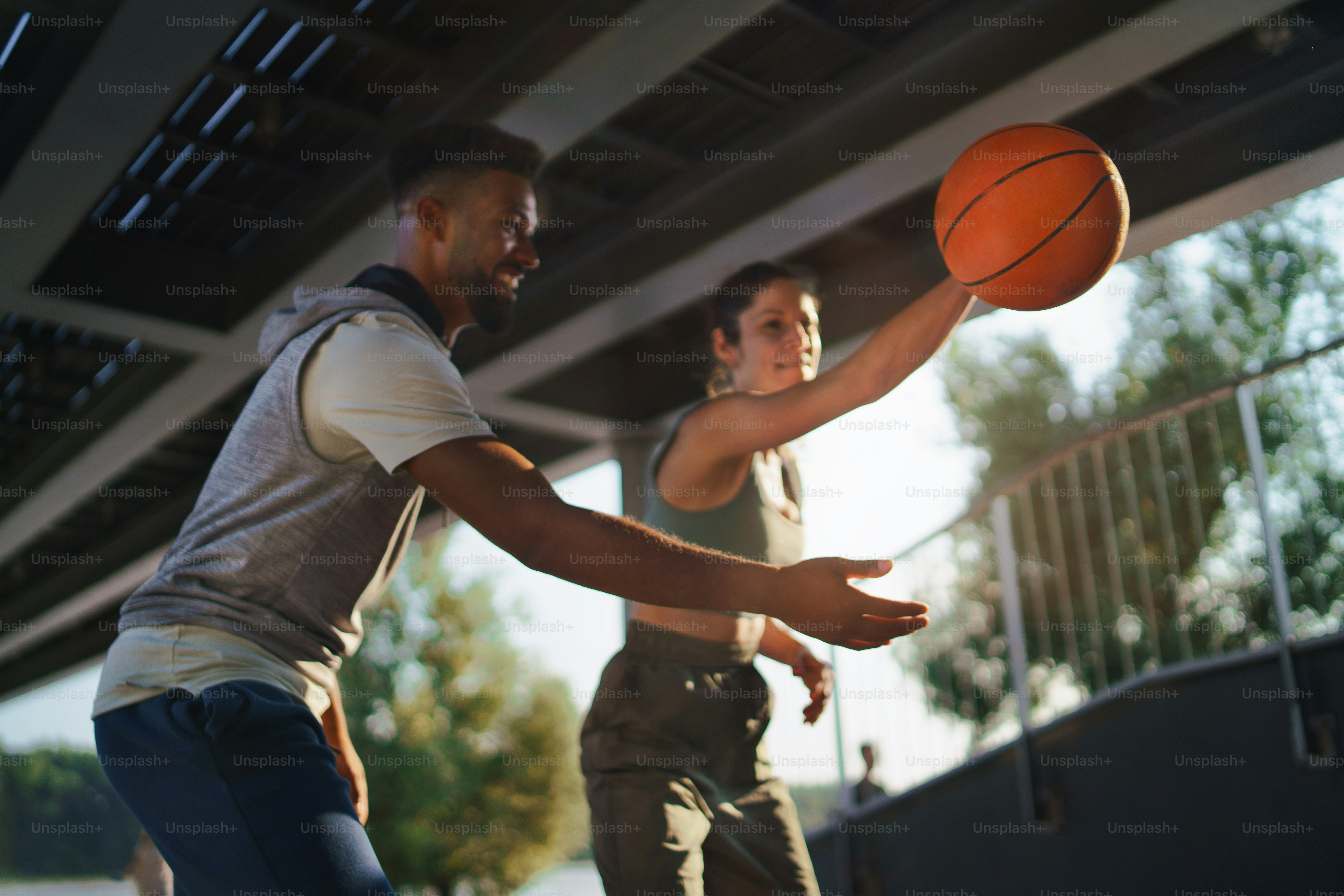 Un hombre y una mujer amigos jugando baloncesto al aire libre en la ...