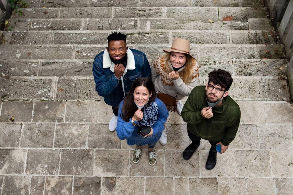 Top view portrait of group of young people outdoors in town, looking at camera. Coronavirus concept.