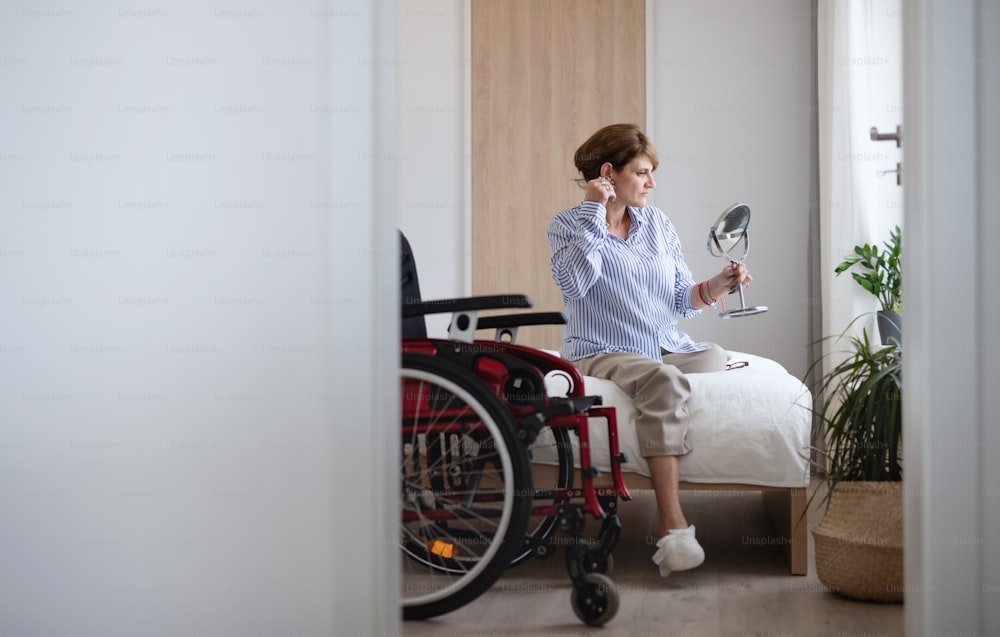 Portrait of disabled mature woman sitting on bed indoors at home, morning routine with leg amputee concept.