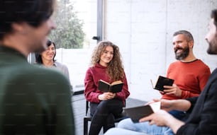 Men and women sitting in a circle during group therapy, reading and talking.