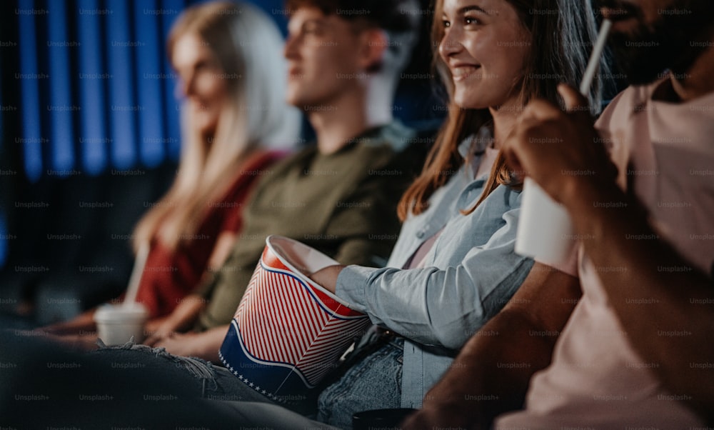 Midsection of unrecognizable cheerful young people sitting in the cinema, watching a film.