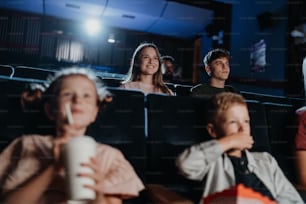 Una alegre pareja joven en el cine, viendo una película.
