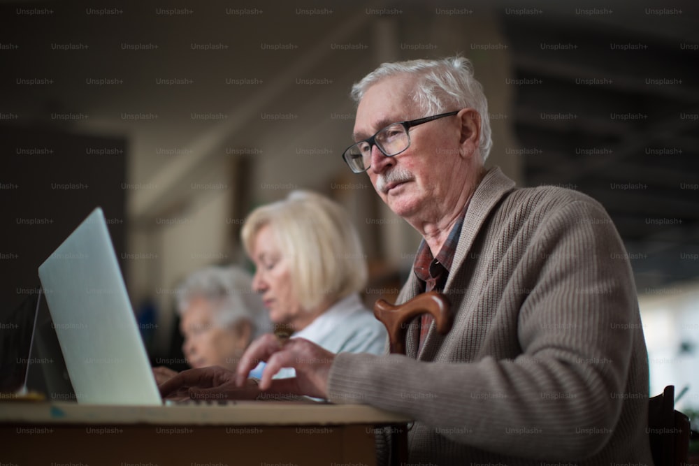 Un gruppo di anziani in una casa di riposo che impara insieme in classe di computer