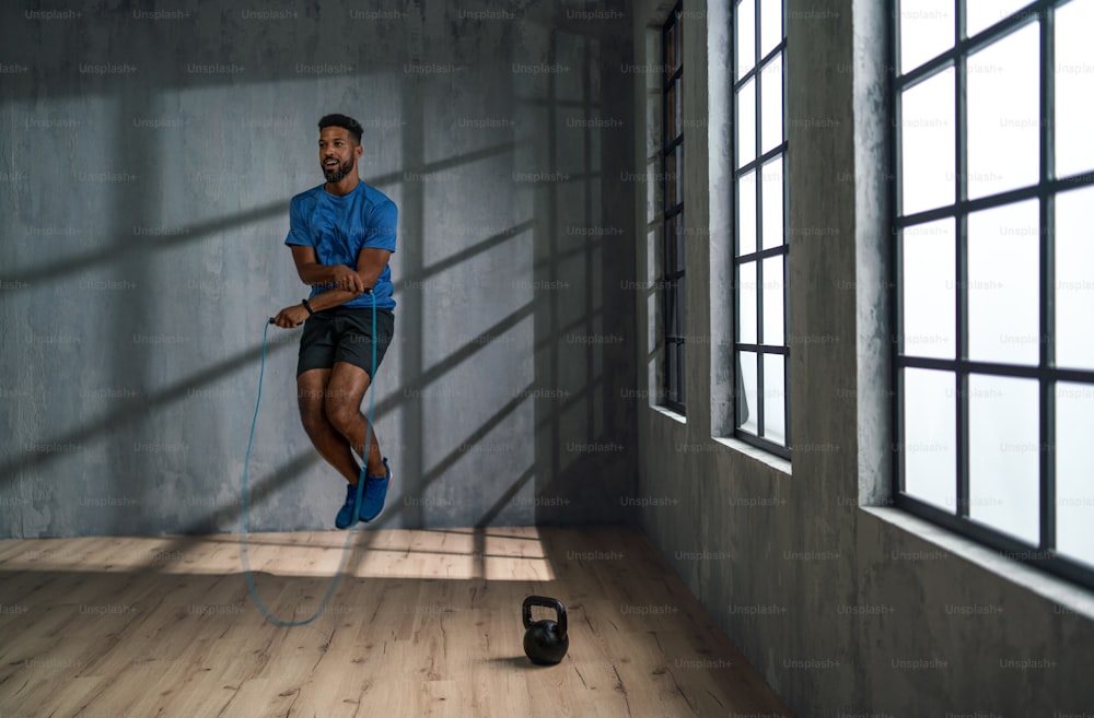 Un jeune sportif afro-américain utilisant une corde à sauter à l’intérieur, concept d’entraînement d’entraînement.