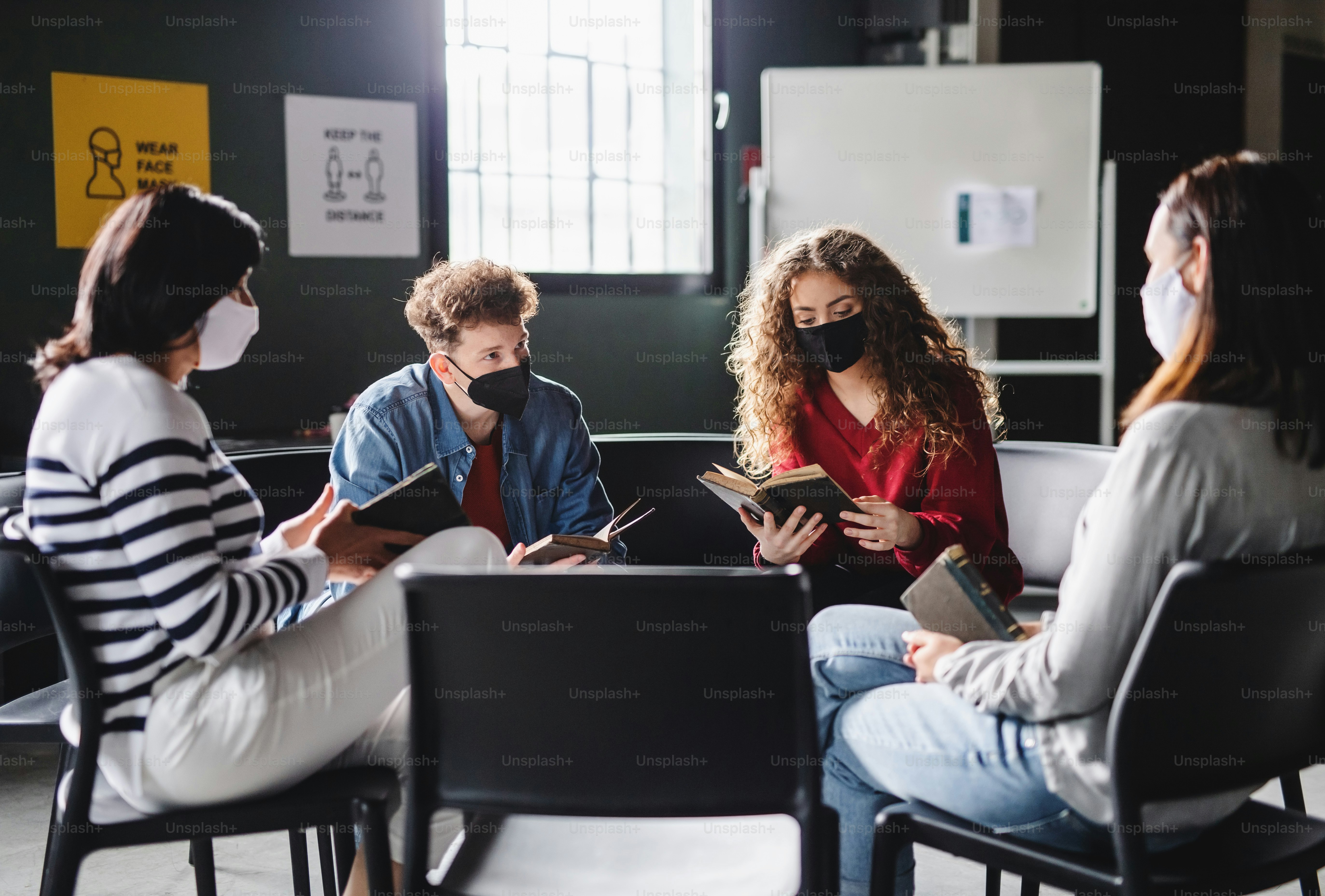 Men and women sitting in a circle during group therapy, reading and talking. Coronavirus concept