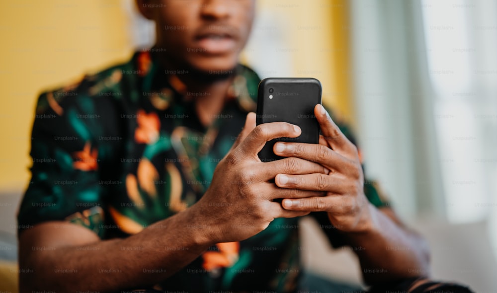 Portrait d’un jeune homme méconnaissable utilisant un smartphone, assis sur un canapé à la maison, concept de réseaux sociaux.