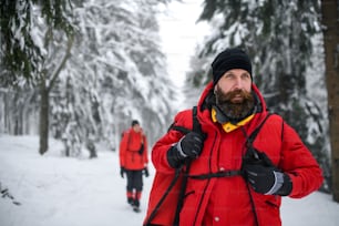 Paramedic man from mountain rescue service with walkie talkie outdoors in a winter in forest.