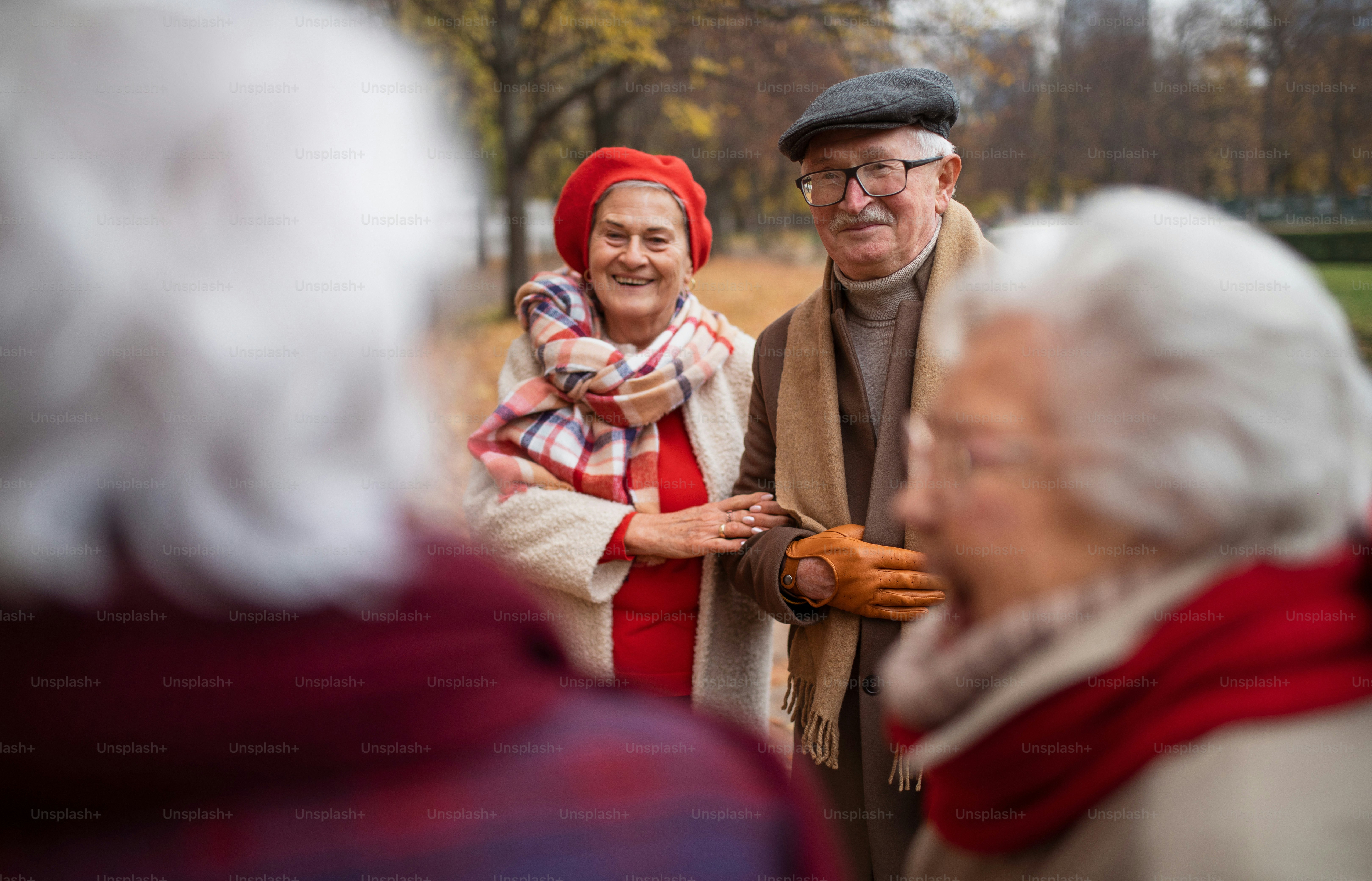 Un grupo de amigos mayores felices en un paseo al aire libre en el parque de la ciudad en otoño, hablando y riendo.
