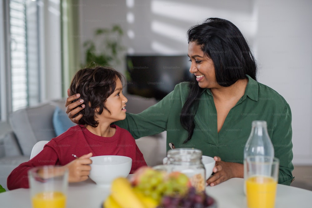 Un niño pequeño desayunando con su madre en casa.
