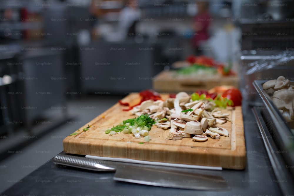 Cut fresh vegetables on a wooden board in commercial kitchen.