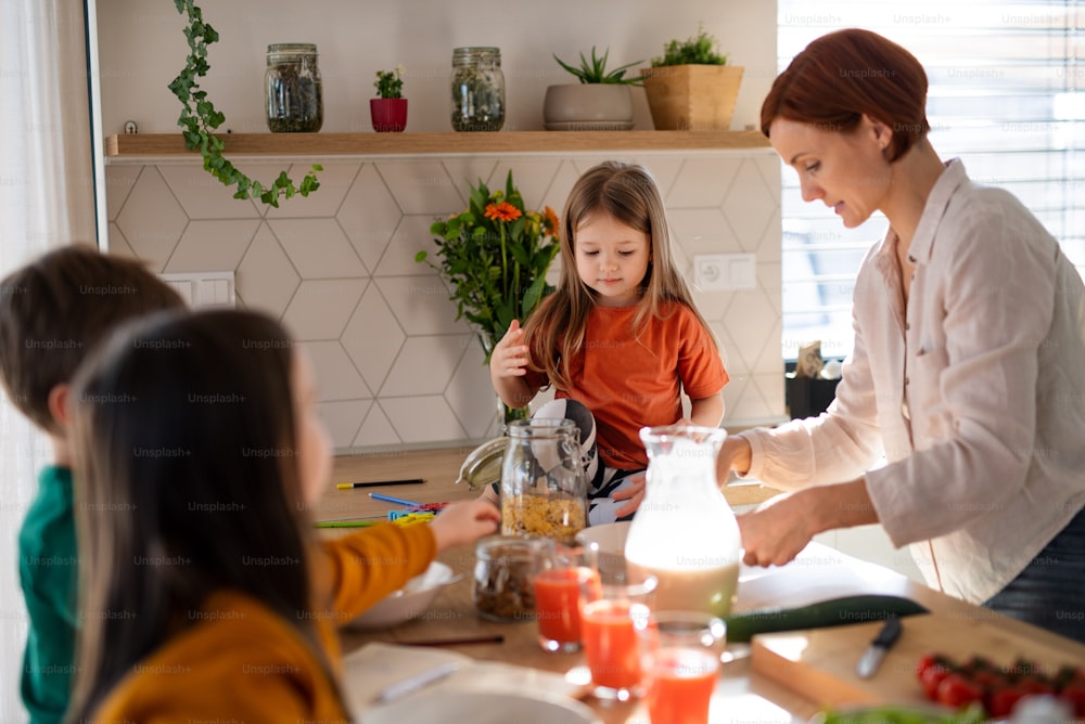 A mother of three little children preparing breakfast in kitchen at home.