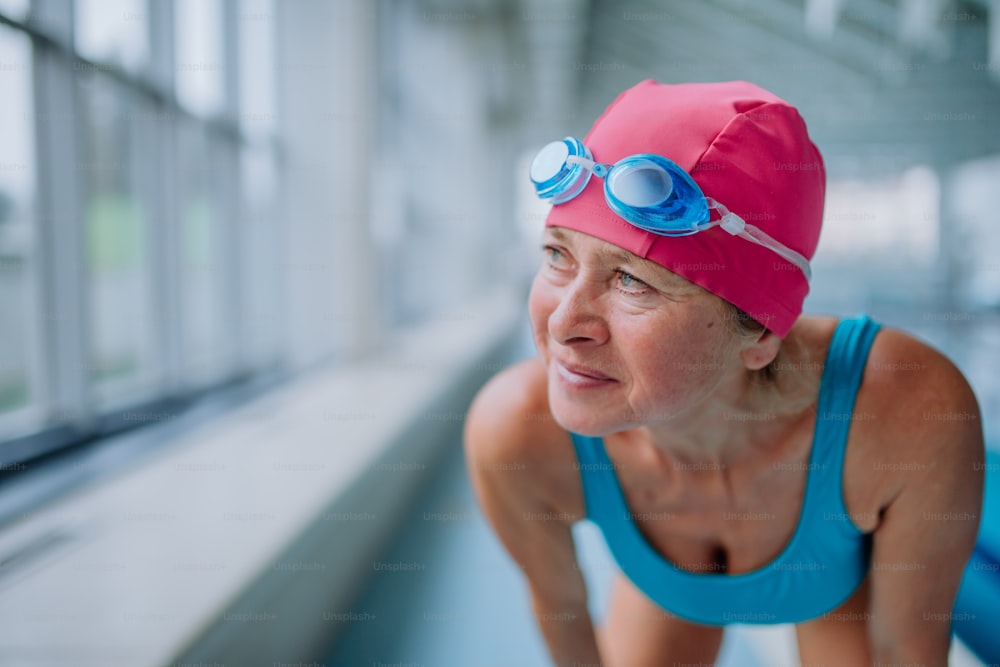 Eine Nahaufnahme einer aktiven älteren Frau, die sich auf das Schwimmen im Innenpool vorbereitet.