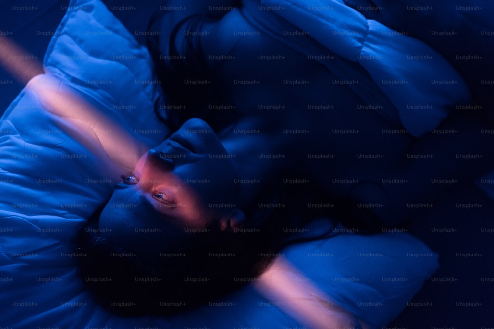 不眠症とうつ病に苦しむ孤独な女性が、夜ベッドで眠れずに横たわっているクローズアップ。