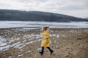 Un ragazzino felice con Down che corre fuori dal lago in inverno.
