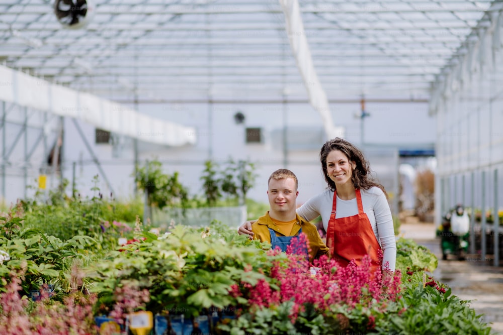 정원 센터에서 다운 증후군을 앓고있는 젊은 직원을 돕는 경험 많은 여성 꽃집.