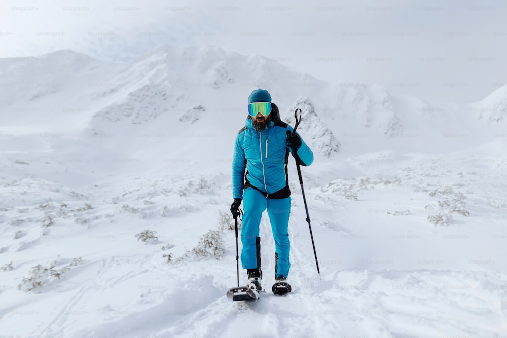 A male backcountry skier hiking to the summit of a snowy peak in the Swiss Alps