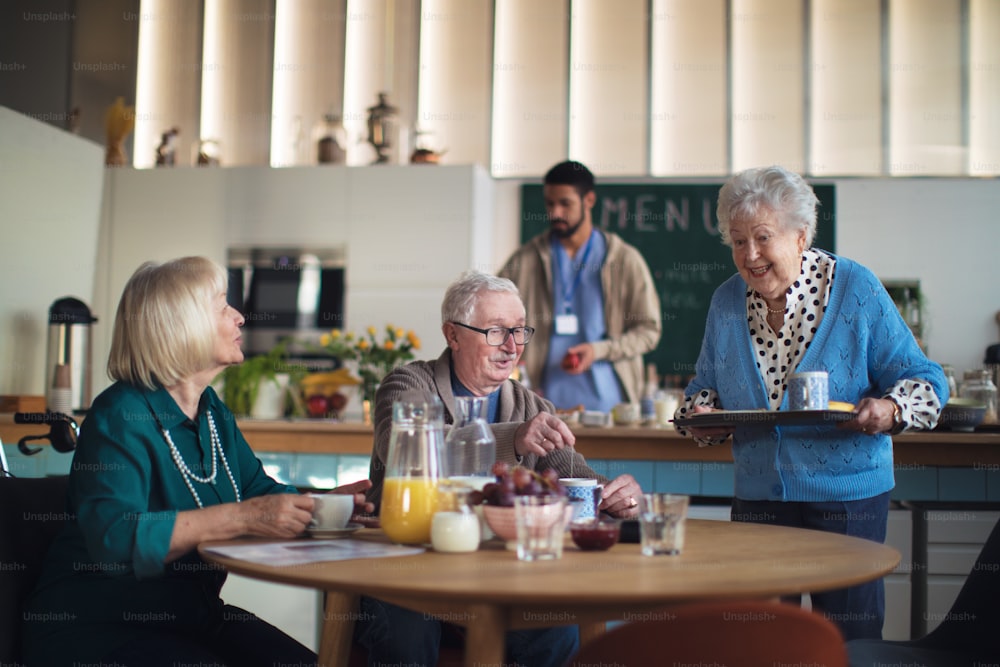 Un grupo de personas mayores alegres que disfrutan del desayuno en el centro de atención domiciliaria.