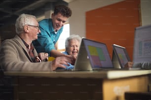A senior group in retirement home with young instructor learning together in computer class