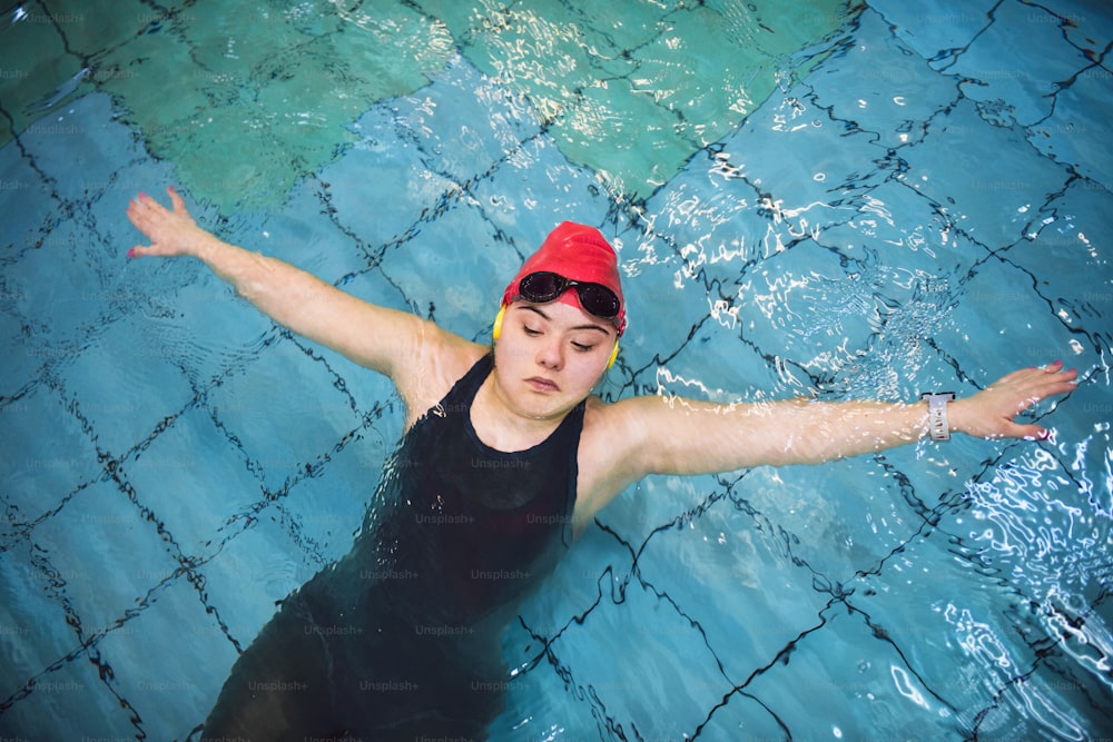 A top view of young woman with Down syndrome swimming in swimming pool