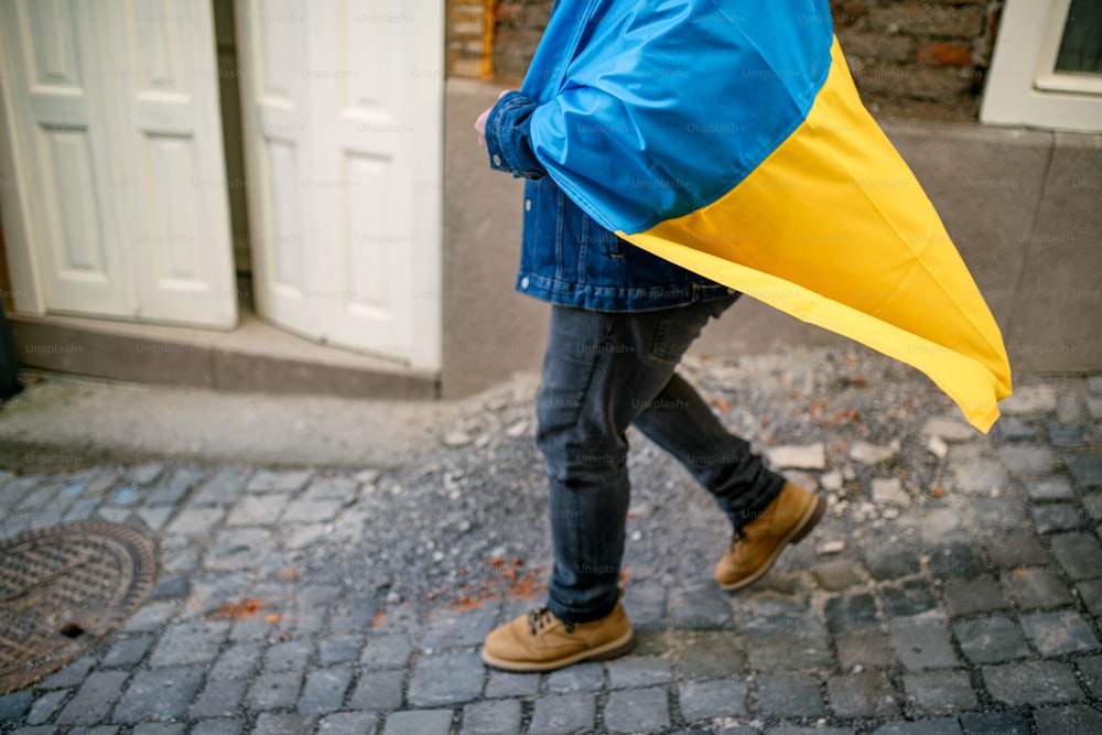 Une partie basse d’un manifestant couvert d’un drapeau ukrainien bleu et jaune proteste contre la guerre en Ukraine dans la rue
