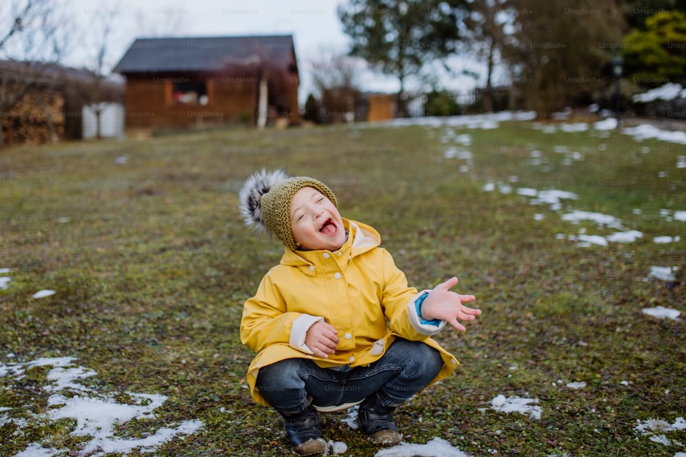 Um garotinho feliz com síndrome de Down do lado de fora no jardim em wnter se divertindo.