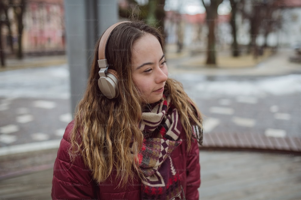 A happy young woman with Down syndrome listening to music in town in winter