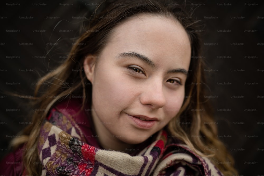 A close-up of young woman with Down syndrome looking at camera on black background