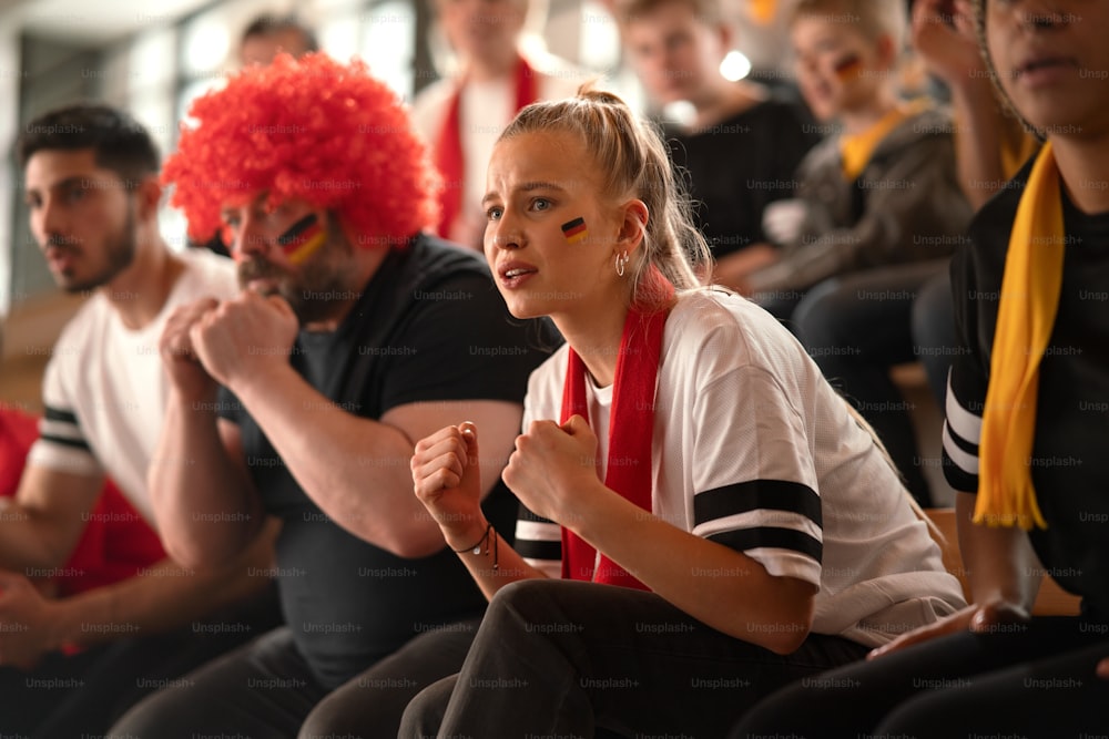 Worried football fans supproting a German national team in live soccer match at stadium.