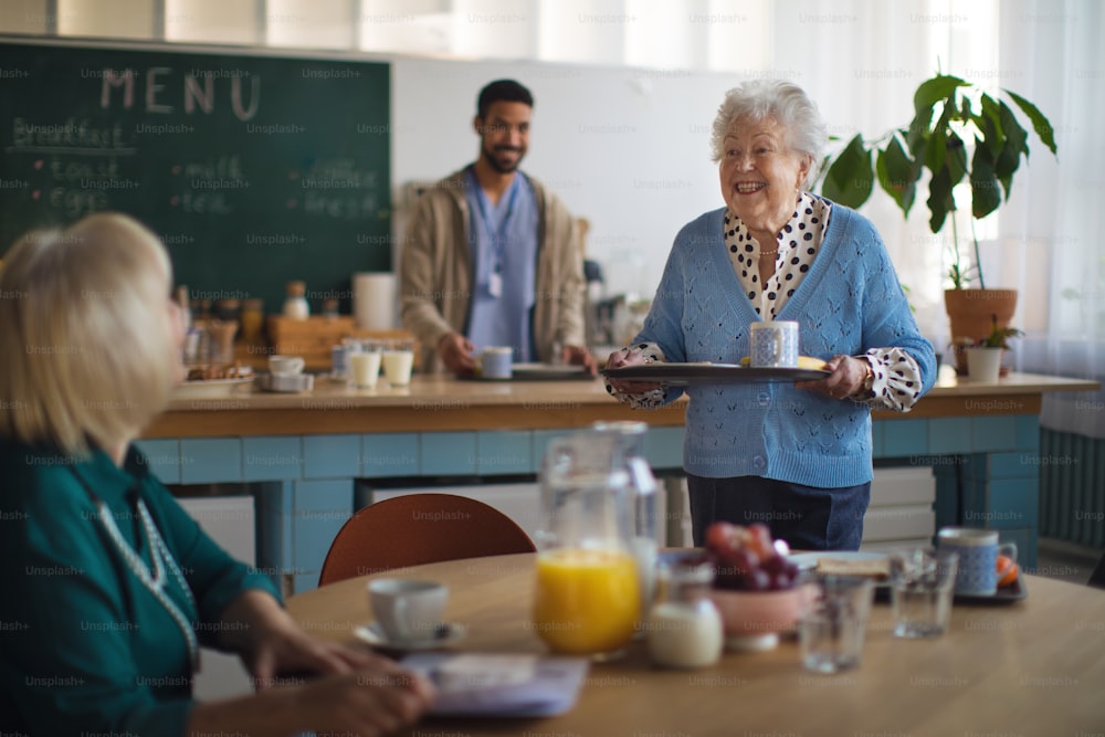 Lächelnde ältere Frauen beim Frühstück in einem Pflegeheim.