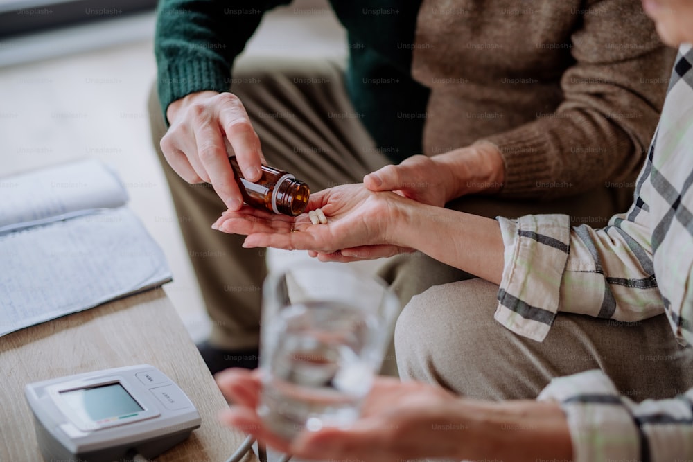 A close-up of senior man giving his wife medication at home