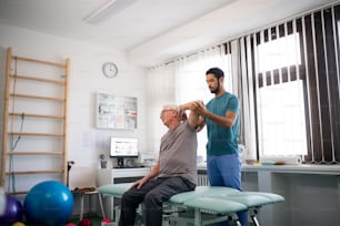 A young physiotherapist exercising with senior patient in a physic room