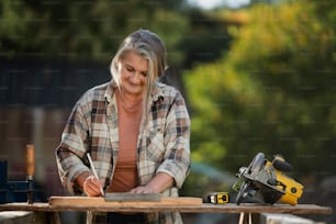 A handy female carpenter working in carpentry diy workshop outdoors