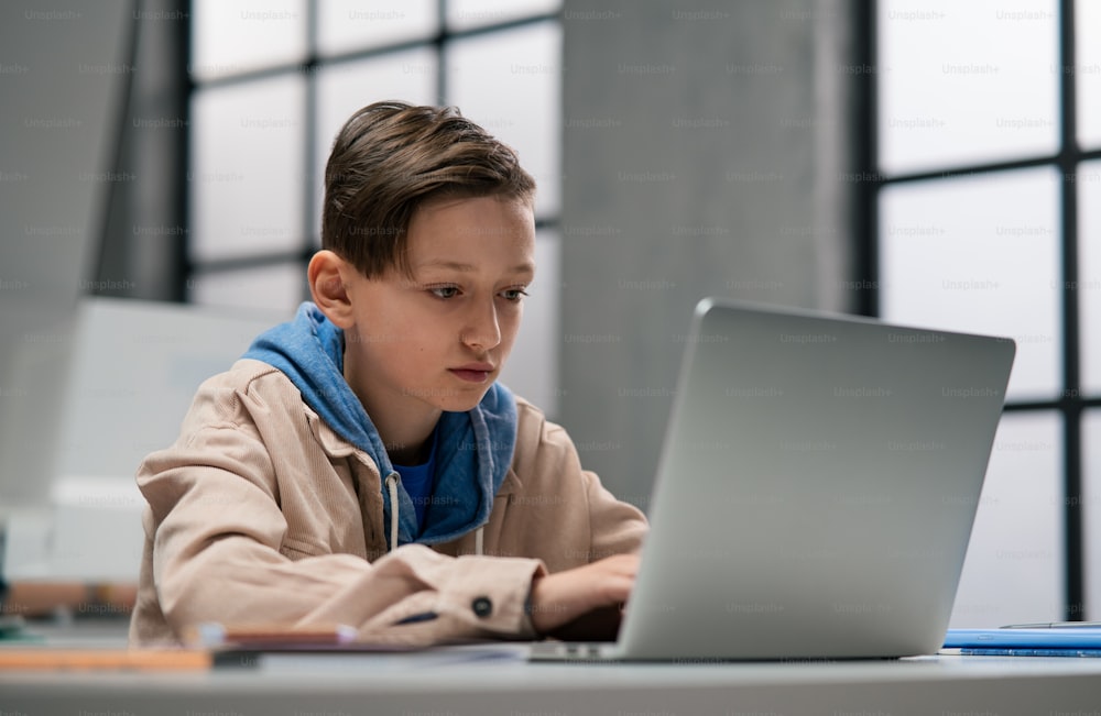 A schoolboy using computer in classroom at school