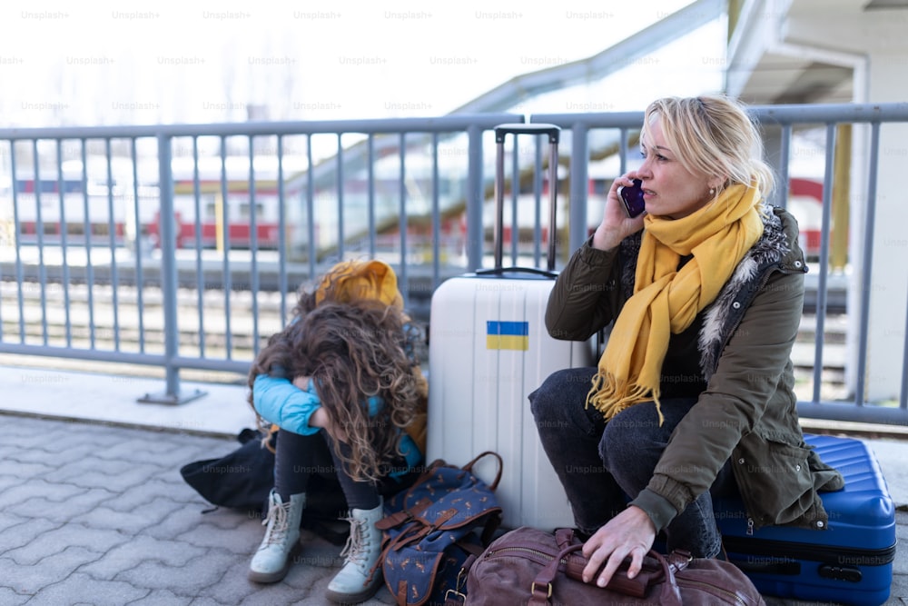 Ukrainian immigrants with luggage waiting at train station, Ukrainian war concept.