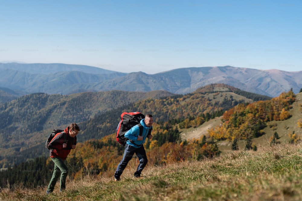 Parapentistes, randonneurs, alpinistes, gravissant une colline jusqu’à un point de départ de parapente, par une matinée ensoleillée en montagne.