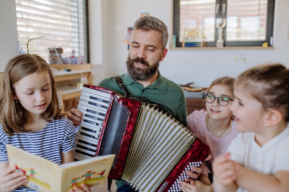 Ein fröhlicher Musikervater spielt Akkordeon für seine drei kleinen Töchter zu Hause.