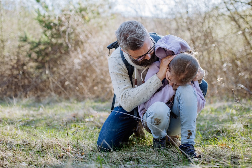 A father with small daughter on walk in spring nature together.