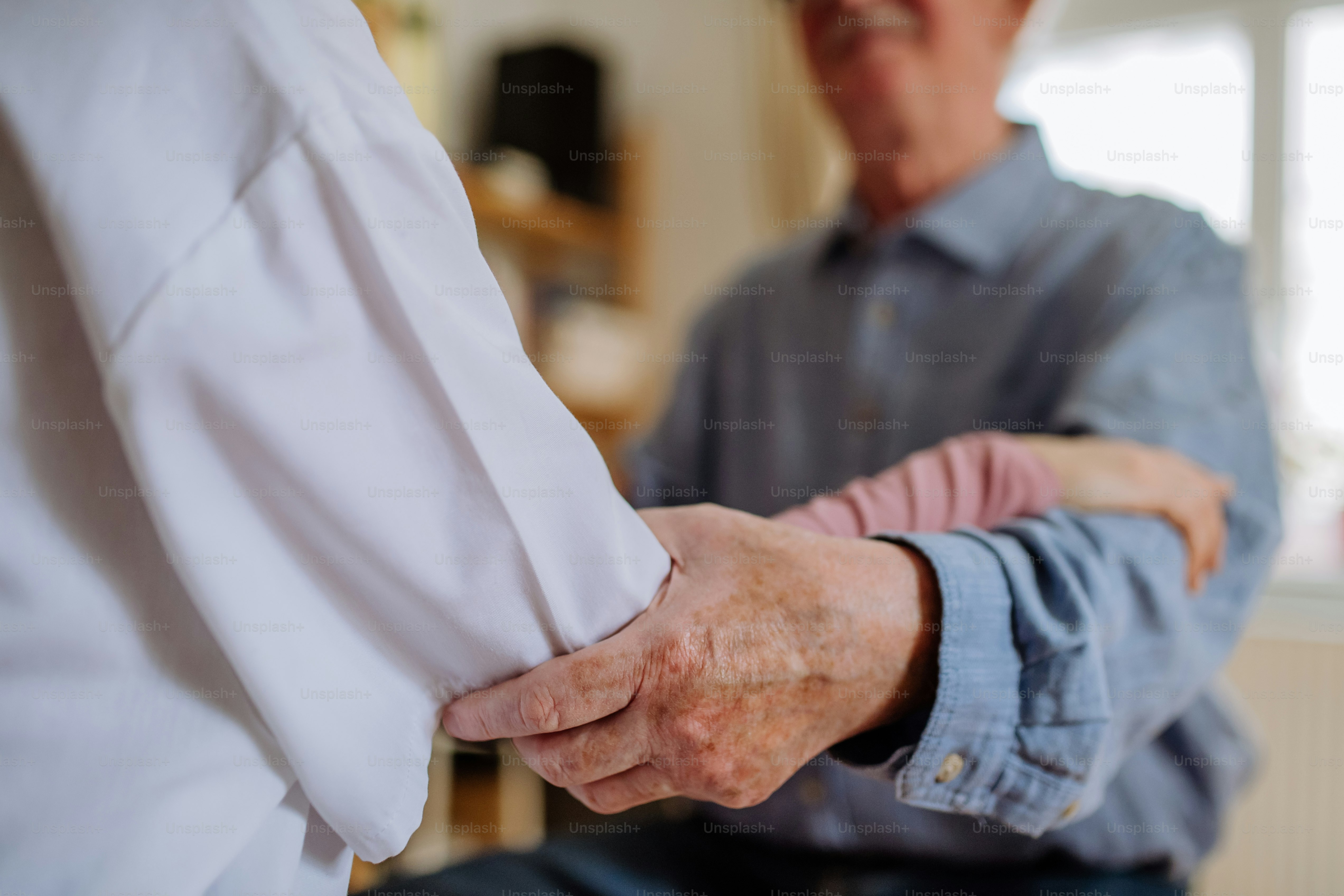 A close-up of doctor holding hand of senior patient and consoling him ...