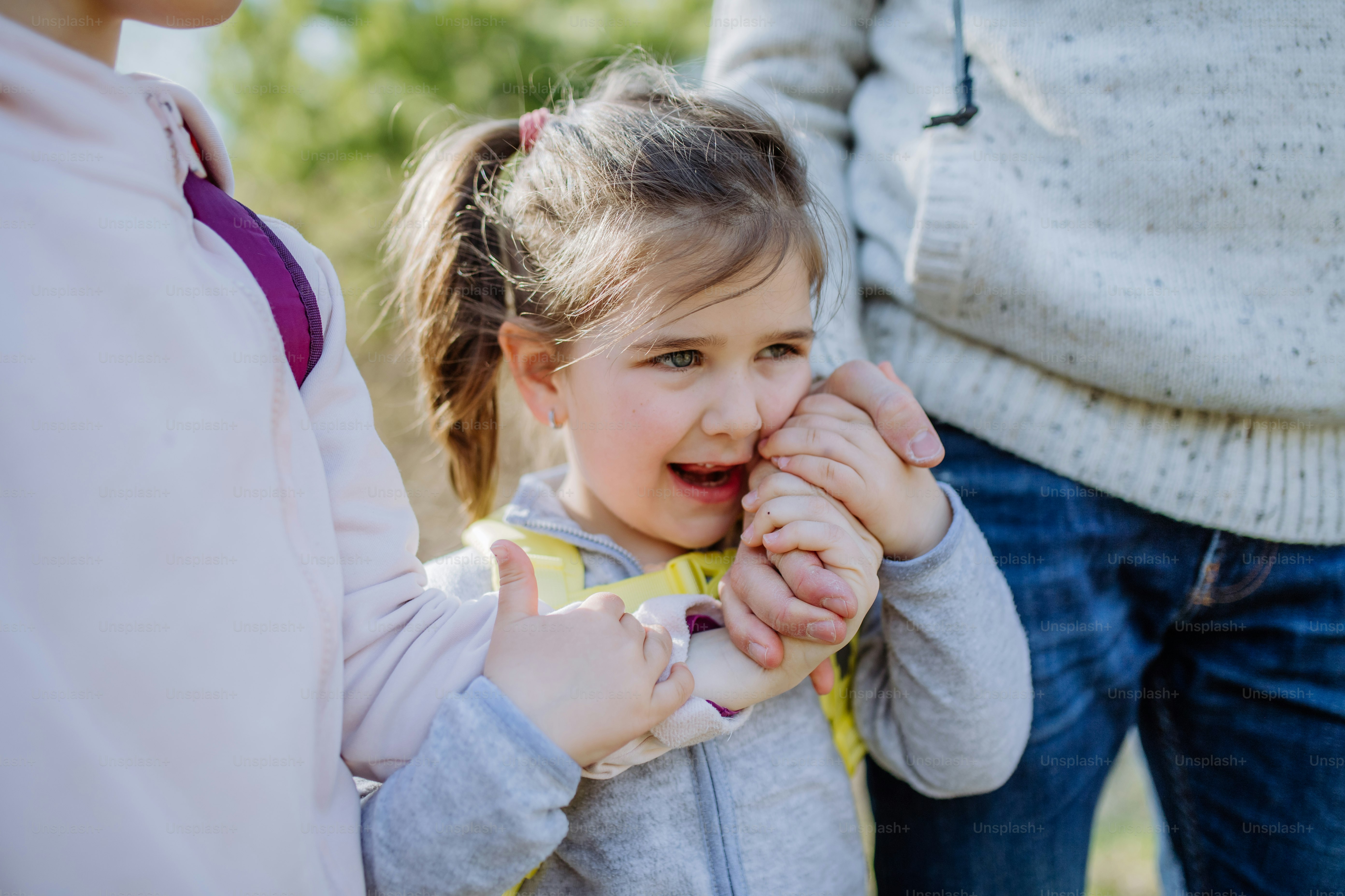 A father and little daughters hold hands on walk in nature