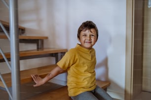 Un ragazzino carino seduto sulle scale di casa.