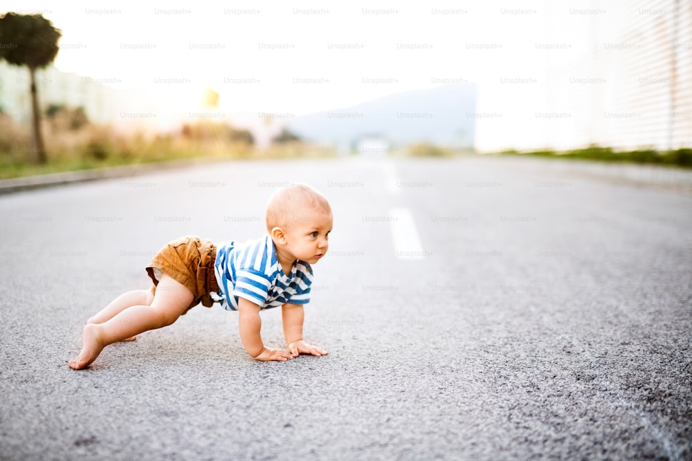 Cute little baby boy crawling outside on the road. Close up.