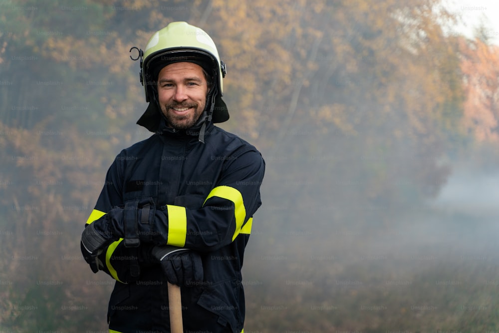Ein Porträt eines glücklichen Feuerwehrmannes, der nach erfolgreichem Einsatz im Wald in die Kamera schaut