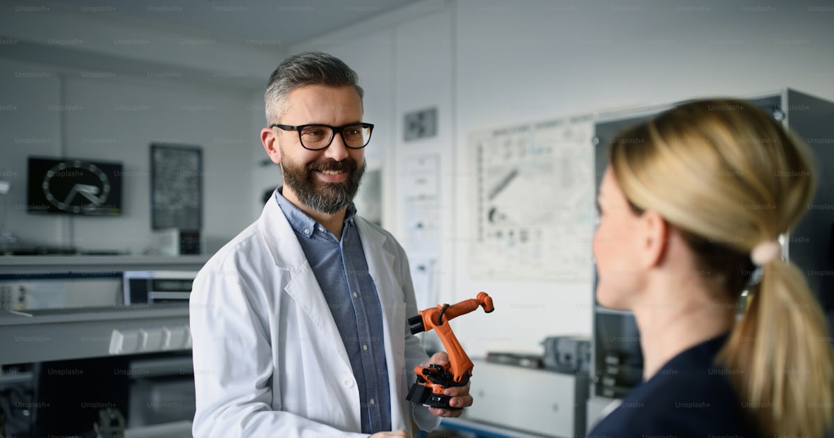 Robotics engineers working and desinging a modern robotic arm in ...