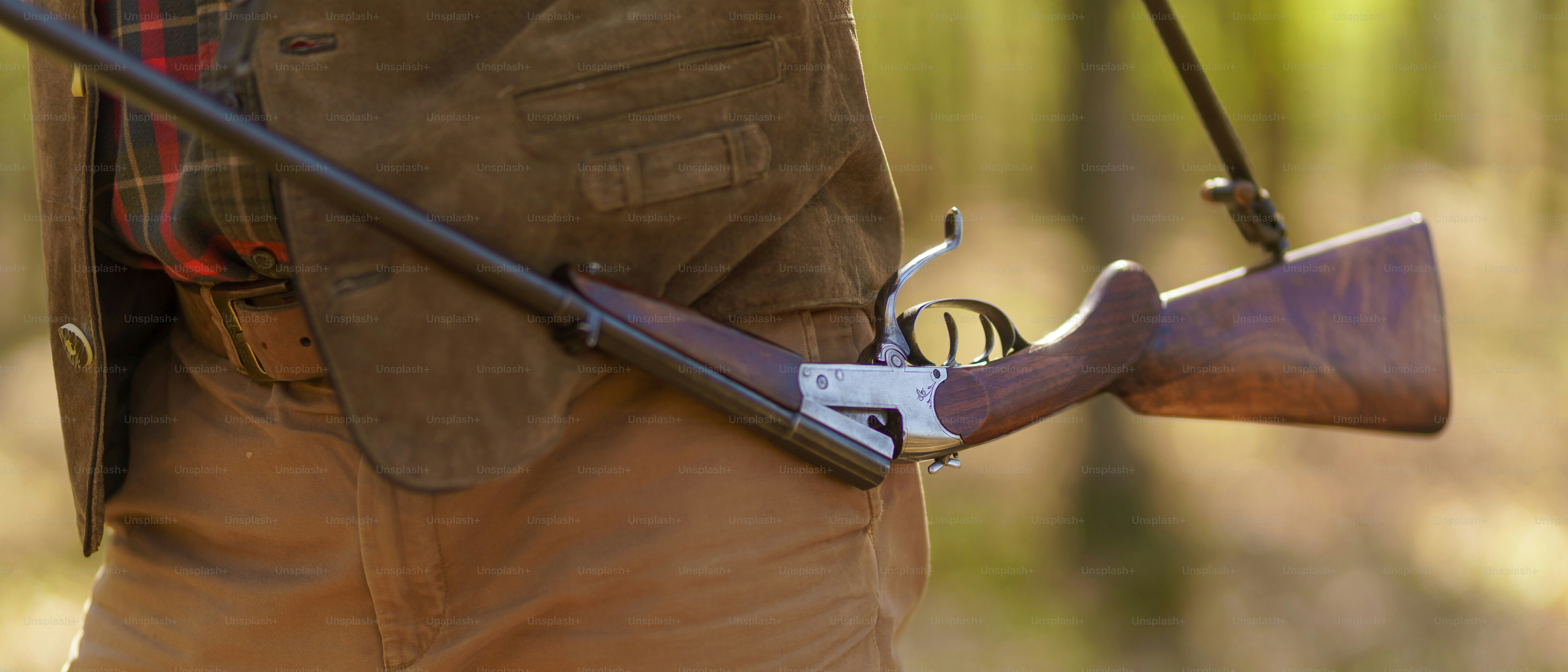 Um close-up de um homem caçador carregando sua arma de rifle na floresta