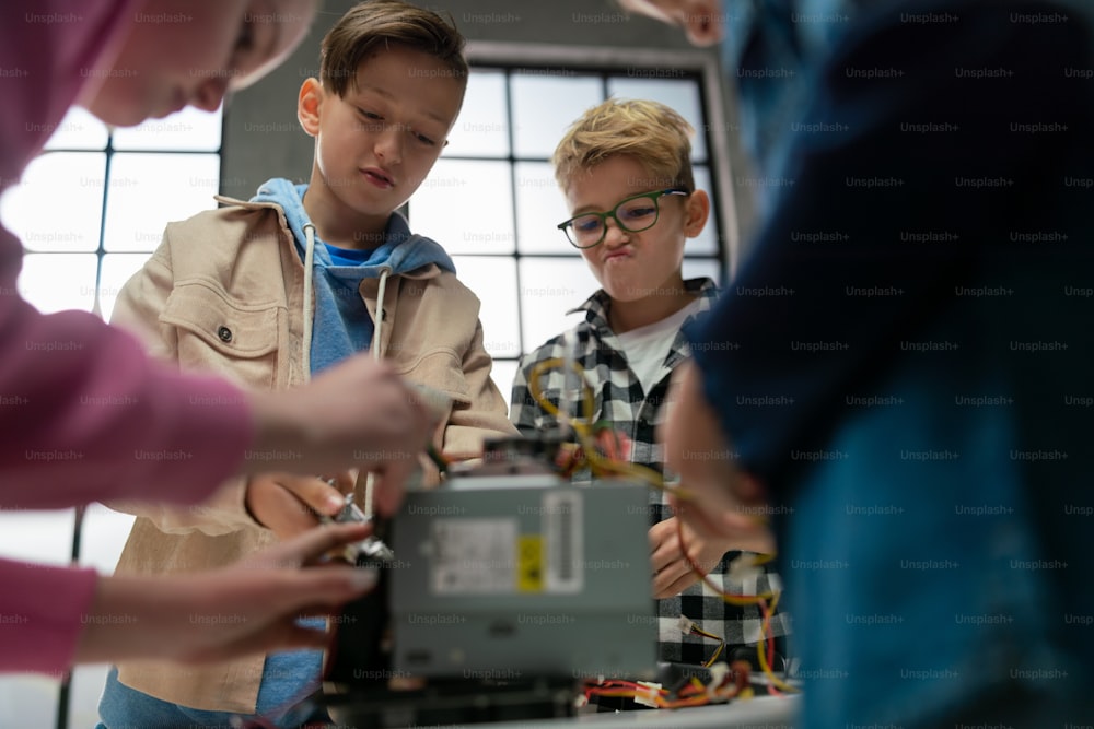 Bambini con un insegnante che lavorano insieme al progetto con giocattoli elettrici e robot in classe di robotica.