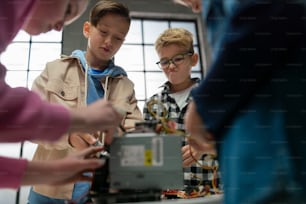 Kinder mit einem Lehrer, der gemeinsam an einem Projekt mit elektrischem Spielzeug und Robotern im Robotik-Klassenzimmer arbeitet.