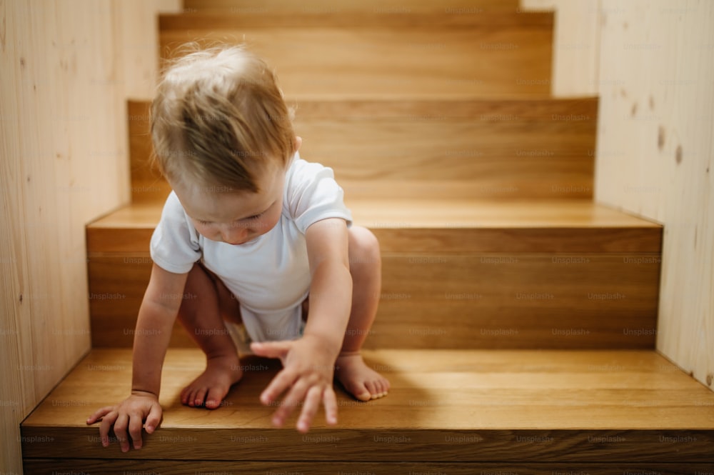 A cute little boy sitting on stairs at home and looking at camera.