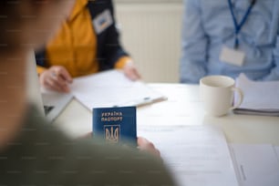 難民センターでウクライナ人女性が書類に記入するのを手伝う年配の女性ボランティア。