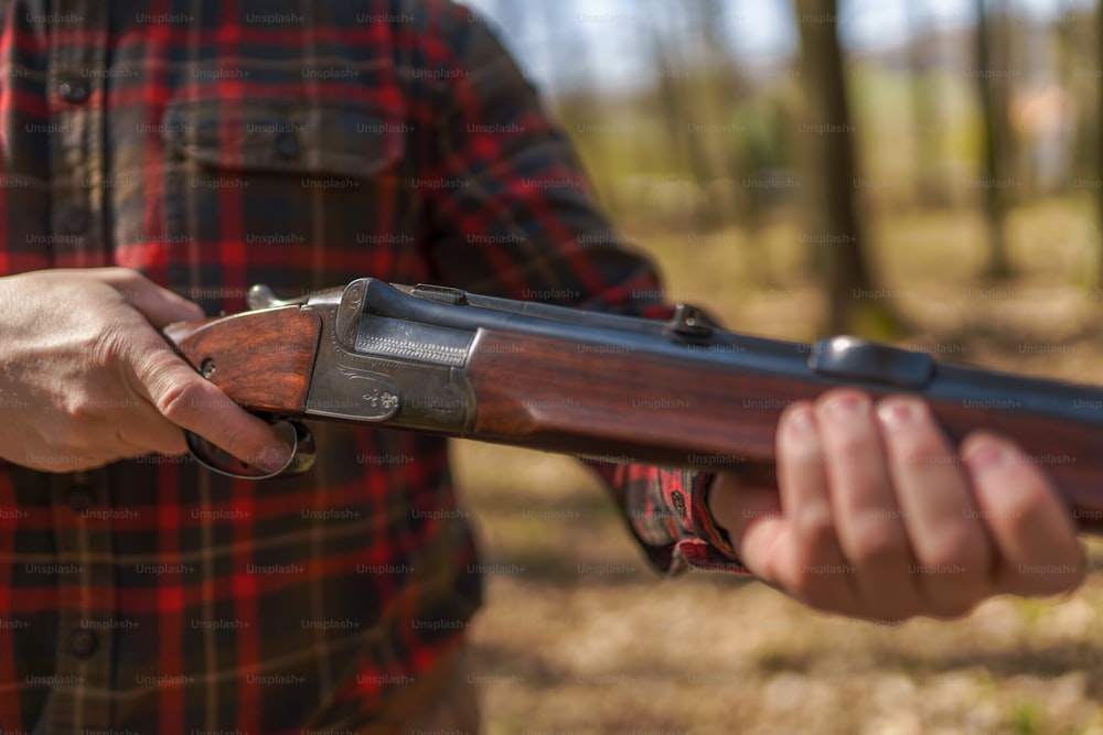 Um close-up do homem caçador carrega o cartucho em uma arma de fuzil na floresta.